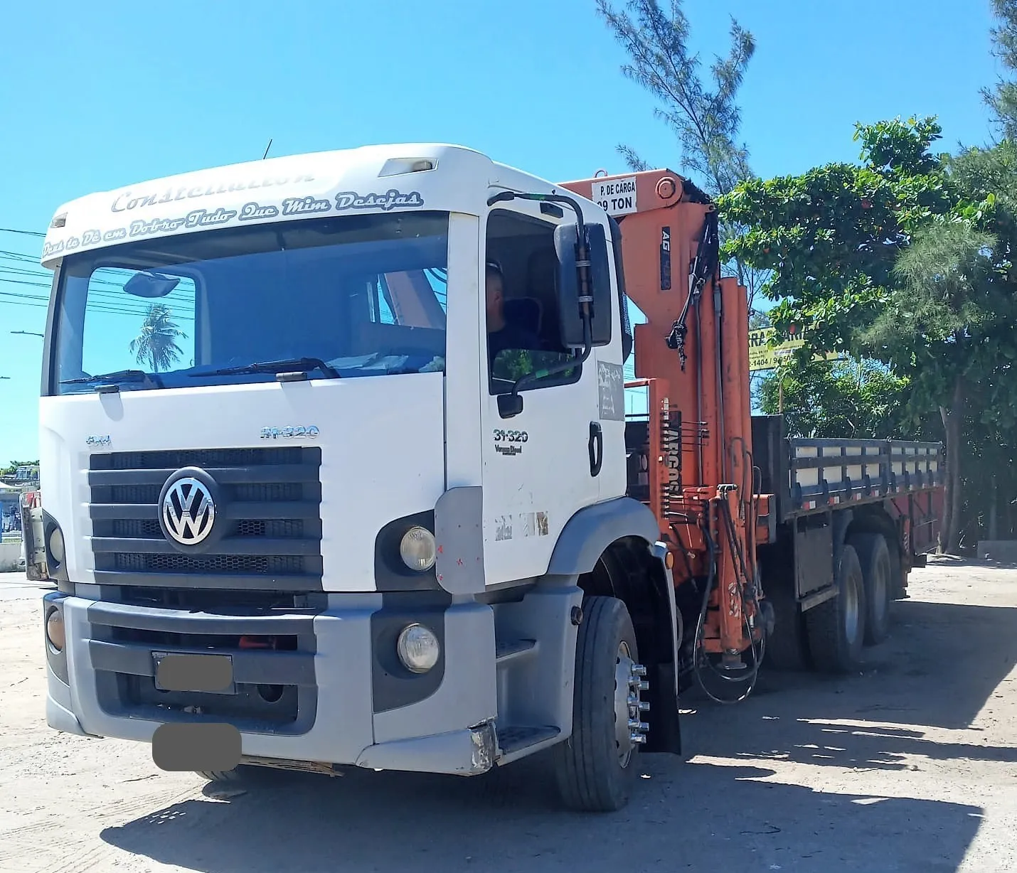 Caminhão munck traçado 6x4 da Becker Ferreira, cabine branca e lança laranja recolhida, com motorista na cabine